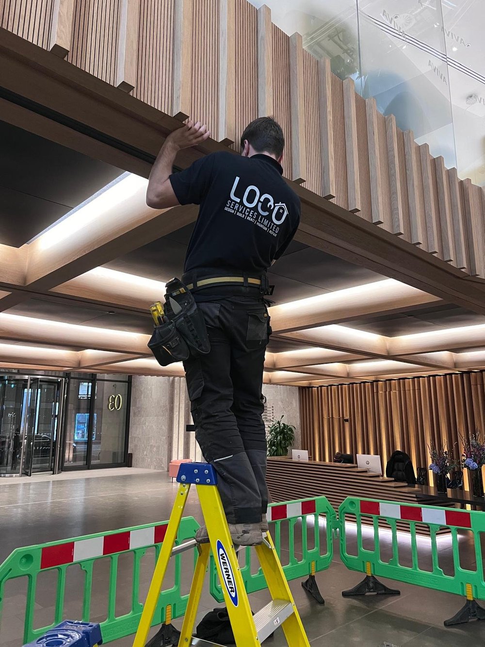 LOCO team member carrying out maintenance on timber details in a commercial building
